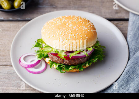 Burger sur une plaque avec des pickles. Fond de bois. Banque D'Images