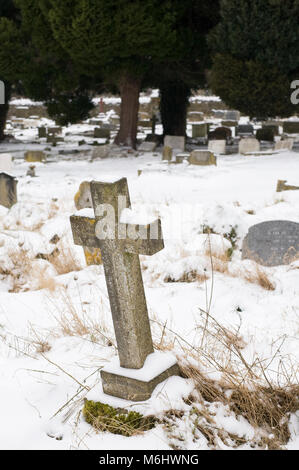 La croix couverte de neige dans un cimetière de l'église. Banque D'Images