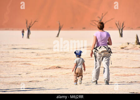 Une mère et un enfant en marchant près des arbres morts ou dans le lac sec près de des célèbres dunes de sable dans la région du parc de Namib Naukluft Sud en Namibie Afric Banque D'Images