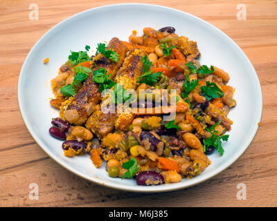 Servant de Cassoulet fraîchement cuisinés saucisses à base de lardons et légumes garnie de persil plat haché dans un bol sur un plateau en bois Banque D'Images