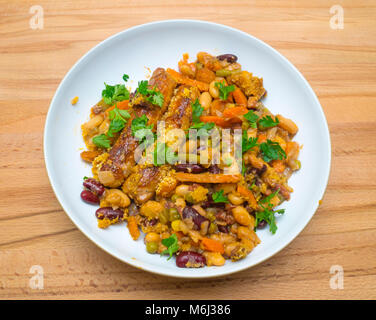 Servant de Cassoulet fraîchement cuisinés saucisses à base de lardons et légumes garnie de persil plat haché dans un bol sur un plateau en bois Banque D'Images