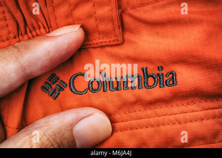 Tambov, Fédération de Russie - Septembre 27, 2017 logo brodé sur Columbia vêtements rouge entre les doigts de personne. Close-up. Banque D'Images