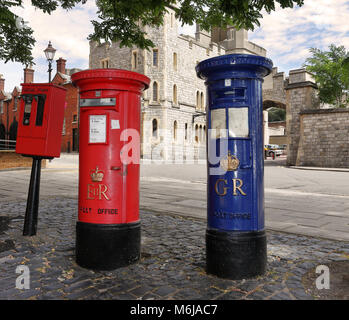 Vintage rouge et bleu English Mail Boxes dans une rue pavée avec une partie du château de Windsor dans l'arrière-plan Banque D'Images