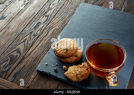 Tasse de thé en verre blanc avec soucoupe en céramique sur les meringues minuscule sur un parquet en bois sombre un vintage, vue du dessus. Banque D'Images