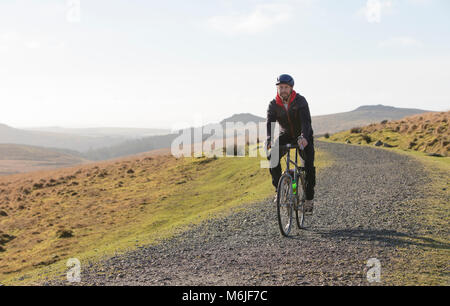 L'homme chevauche son vélo le long d'une arête sur Dartmoor National Park, Devon Banque D'Images