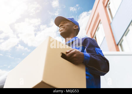 Low Angle View Of Loader Homme debout près du Van Holding Cardboard Box Banque D'Images