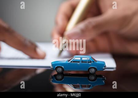 Signature de l'accord de prêt de voiture Contrat avec location de jouet sur Bureau en verre Banque D'Images