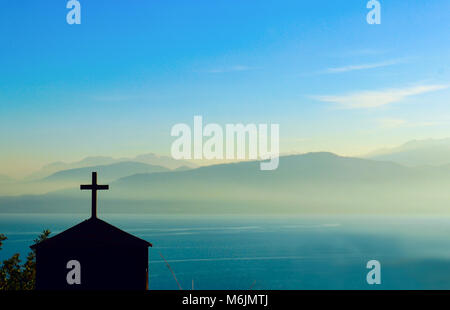 Silhouette de bâtiment avec croix en haut en face de la plage de montagne brouillé par épais brouillard de l'autre côté de la Manche Banque D'Images