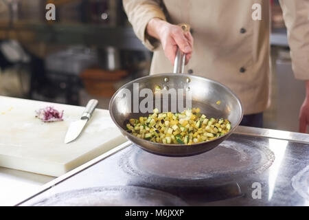 Chef holding poêle avec tranches de légumes. Banque D'Images