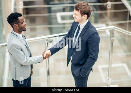 Deux hommes d'multiraciale handshaking in modern office pour fin de grande Banque D'Images