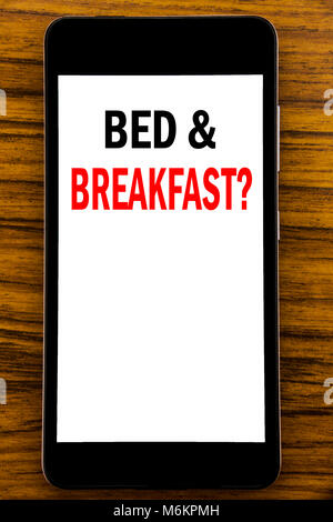 Texte d'annonce d'écriture montrant Bed Breakfast. Concept d'affaires pour les vacances voyage billet écrit sur téléphone portable mobile avec fond de bois w Banque D'Images