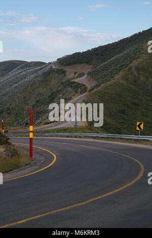 Deux voies d'enroulement par région Alpes Australiennes avec bandes jaunes, signes courbe neige rouge poteaux et de collines et montagnes arrondies Banque D'Images