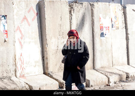 Kalandia, Palestine, 12 Janvier 2011 : une femme passe un mur de béton près de check point de Kalandia, construit par Israël pour empêcher les Palestiniens le navettage dans Banque D'Images