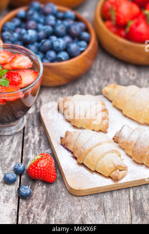 Des croissants frais et des baies avec une tasse de thé sur la vieille table en bois Banque D'Images