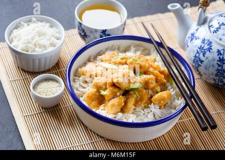 La cuisine chinoise bol de riz avec le poulet et les graines de sésame, Chine théière et thé vert. Fond bambou makisu Banque D'Images