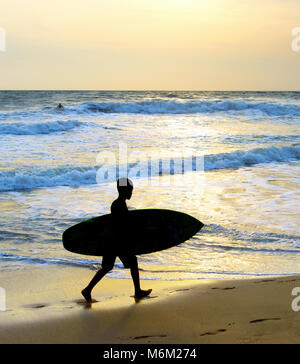 Garçon surfer la marche sur la plage avec une planche de surf . L'île de Bali, Indonésie Banque D'Images