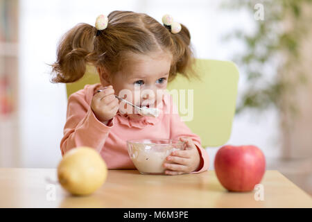 Fille enfant de manger du yogourt ou fromage frais avec des fruits. Banque D'Images