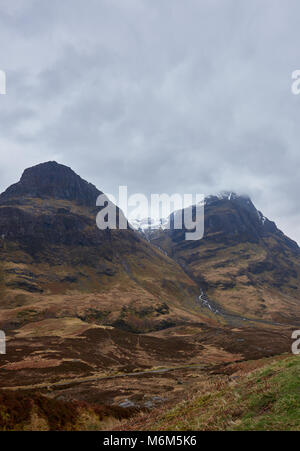 Deux des trois soeurs à Glen Coe écossais sur un jour de printemps en avril. Les nuages bas et brouillard écossais se prêter à la scène de théâtre.. Banque D'Images