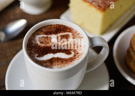 Libre d'une tasse de Cappuccino avec une paire de lunettes et une moustache dessiné avec du cacao en poudre sur sa mousse, sur un set de table pour le petit déjeuner Banque D'Images