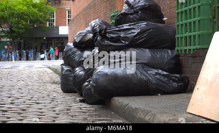 Sacs à déchets noirs s'asseoir le long d'une rue de ville calme en attente d'être recueillis par l'assainissement. L'établissement d'angle bas droit avec une rue de Brooklyn en th Banque D'Images