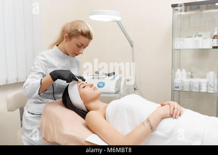 Cosmétologie matérielles. Cosmetologist faire Procédure de nettoyage aux ultrasons de visage. Young woman getting peeling ultrasonique en instituts de beauté. Cosmetolog Banque D'Images