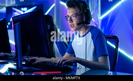 Tiré d'un jeune capitaine de l'équipe de joueur commandes donnant dans le microphone. Il joue en multijoueur jeu vidéo d'une Tournoi eSport. Banque D'Images