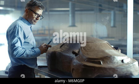 Chef Designer automobile voiture futuriste avec Rake sculpte l'argile à modeler à partir du modèle. Il travaille dans un studio situé dans une grande usine automobile. Banque D'Images