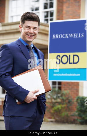 Homme debout à l'extérieur de l'agent immobilier Propriété résidentielle avec Sold Sign Banque D'Images