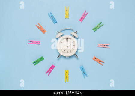 Creative concept minimal des clothespins en cercle et petit réveil au milieu sur fond bleu pastel Banque D'Images