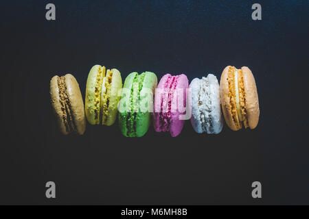 Macarons colorés très détaillés sur fond noir concept minimal Banque D'Images