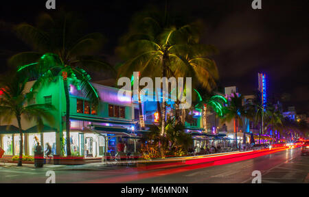 Ocean Drive à Miami dans la nuit avec des couleurs de la rue. Voitures qui passent par la création de lignes de lumière pendant une longue exposition. Palms hotel, en arrière-plan. Banque D'Images