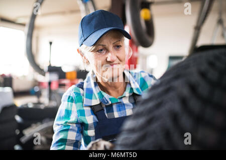 Senior female mechanic repairing une voiture dans un garage. Banque D'Images