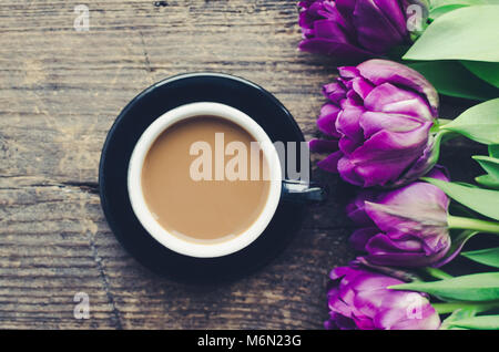 Tasse de café avec du lait et bouquet de tulipes violet sur fond de bois ancien. Le petit-déjeuner sur la fête des mères, Saint Valentin ou le jour de la femme. M romantique Banque D'Images
