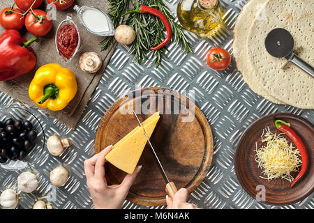 Vue partielle de la femme la découpe du fromage pendant la cuisson de la pizza italienne maison Banque D'Images