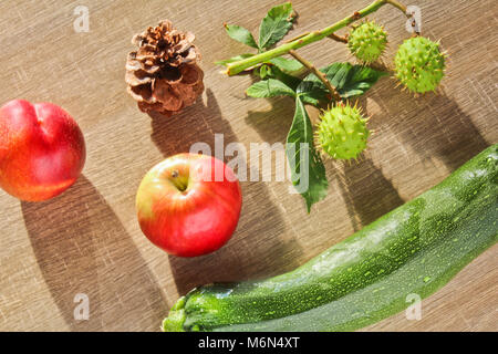 Fruits d'automne, cône, châtaignes, nectarine apple et le concombre sur fond de bois Banque D'Images