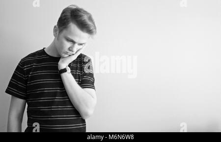 1960 Style : Noir et blanc portrait of young man. Il se sent triste avec sa tête sur sa main. Banque D'Images