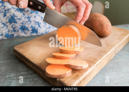 Close Up of Woman Preparing Sweet Potato sur planche à découper Banque D'Images