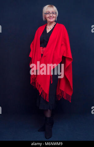 Portrait of attractive blonde woman standing avec grand châle rouge Banque D'Images