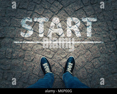 Vue de dessus d'un homme en noir sneakers sur fond des chaussées urbaines debout à côté de la ligne de départ. Démarrage d'un nouveau défi concept. Banque D'Images