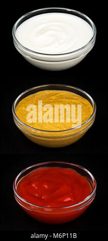 Ketchup, mayonnaise et moutarde dans des bols en verre isolé sur fond noir Banque D'Images