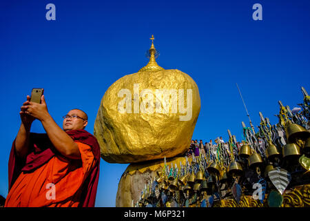 Un moine bouddhiste prend un à la Pagode Kyaiktiyo selfies, le Golden Rock, au sommet de Mt. Kyaiktiyo, l'un des plus importants lieux de pèlerinage o Banque D'Images