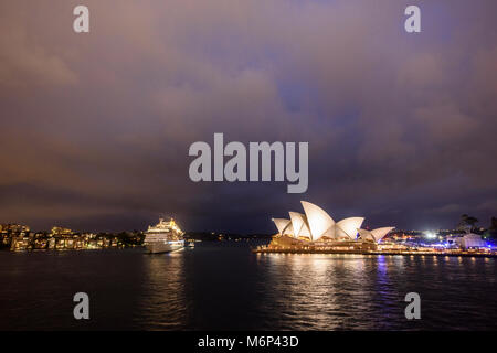 Le port de Sydney avec bateau de croisière illuminé et Opéra de Sydney au crépuscule sous ciel d'orage. Banque D'Images