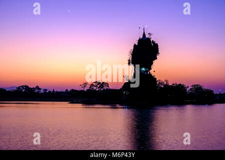 La pagode de Kyauk Ka Lat, vu au coucher du soleil, appartient à un monastère et est situé sur une île au milieu d'un lac Banque D'Images