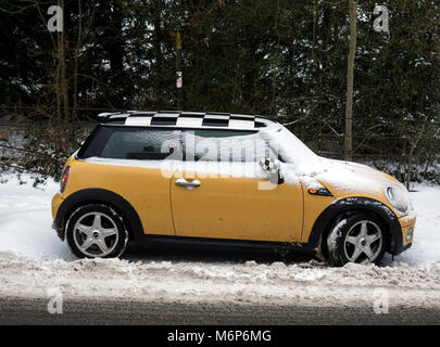 Une voiture Mini Cooper jaune garée dans la neige, UK Banque D'Images