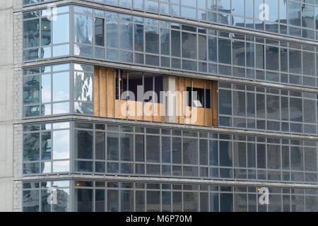 Broken Glass skyscraper éliminé de la façade de l'immeuble en milieu urbain ville. Les planches de bois du pli à l'extérieur du bloc de verre jusqu'à ce que les éléments de construction fixes par repairm Banque D'Images