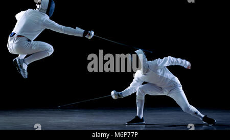 Deux tireurs professionnels montrent de l'Épée de Maître dans leur lutte d'aluminium. Ils Dodge, Leap et de poussée et sur une jambe. Shot isolé sur fond noir. Banque D'Images