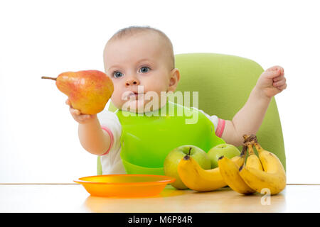 Avoir un bébé table pleine de fruits sains. Cheerful toddler holding de poire. Isolé sur fond blanc Banque D'Images