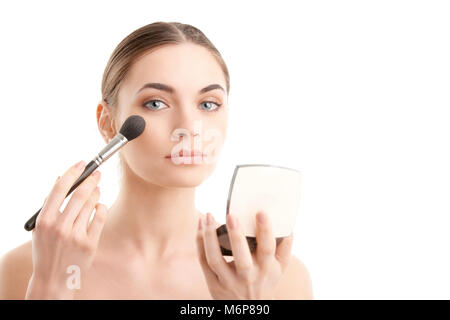 Close-up of a young woman holding pinceau dans la main et appliquer le maquillage. Isolé sur fond blanc. Banque D'Images