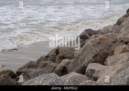 La ligne de gros rochers côte de l'océan mer plage comme les vagues déferlent jusqu'à l'encontre de l'actuel Banque D'Images