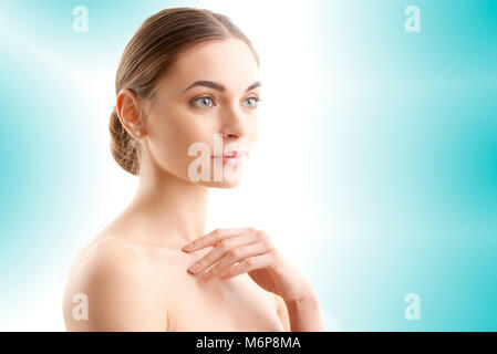 Close-up portrait of a Beautiful woman smiling et réfléchie tout en se posant contre légères isolées à fond bleu. Banque D'Images